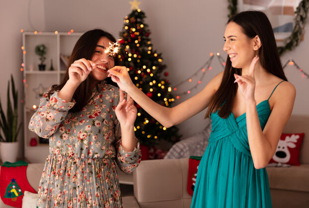 火花笑容可掬的年轻姑娘们在家里享受圣诞时光穿越家年轻
