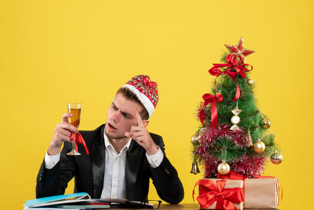 小正面图：男性工人在庆祝圣诞节时 用香槟围着圣诞树 并在黄色的圣诞树上献礼人年颜色