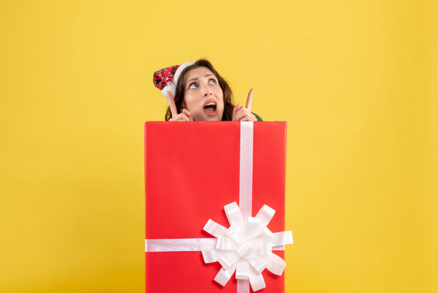 礼物站在黄色墙上盒子里的年轻女子的正视图丝带里面购物