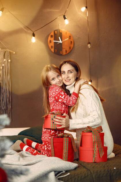 礼物人们在为圣诞节做准备母亲在和女儿玩耍一家人在节日的房间里休息红色圣诞树