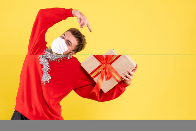 冠状病毒正面图年轻男子手持圣诞礼物颜色礼物丝带