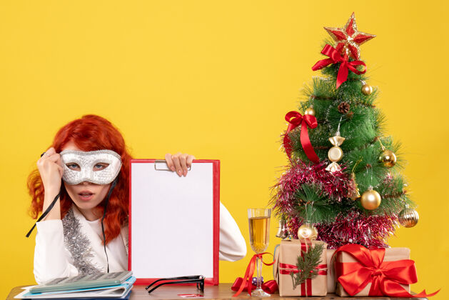 情感女医生戴着面具围着圣诞树 黄色的礼物圣诞庆祝丝带