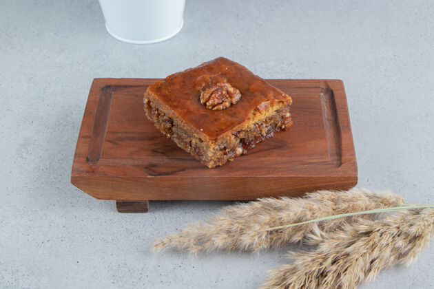 甜Bakhlava在一个小板子旁边的一捆羽毛草秸秆大理石背景上茎羽毛草美味