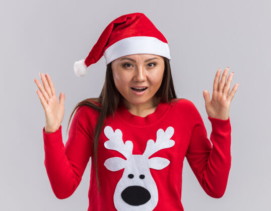 惊喜惊讶的年轻亚洲女孩戴着圣诞帽和毛衣 在白色背景上显示出孤立的尺寸帽子尺码年轻