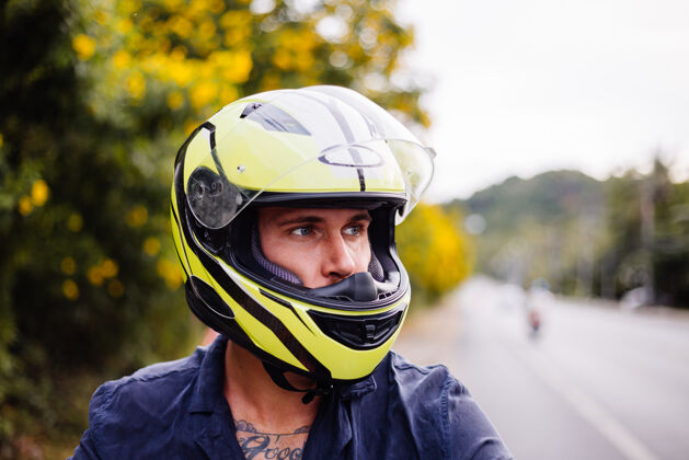 车辆在泰国繁忙的公路边骑摩托车的戴着黄色头盔的男摩托车手的画像时尚街道出租