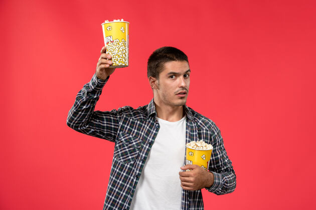 歌手正面图年轻男子手持爆米花包在淡红墙电影院看电影电影院浅红色电影