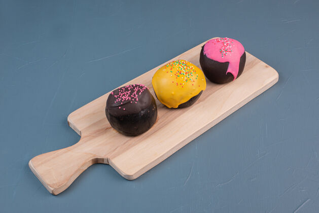 食物三个甜甜圈在木板上甜甜圈粉色巧克力色