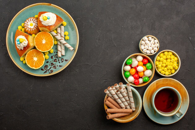 早餐顶视图美味的派片与新鲜的橘子茶和糖果在黑暗中茶糖果晚餐
