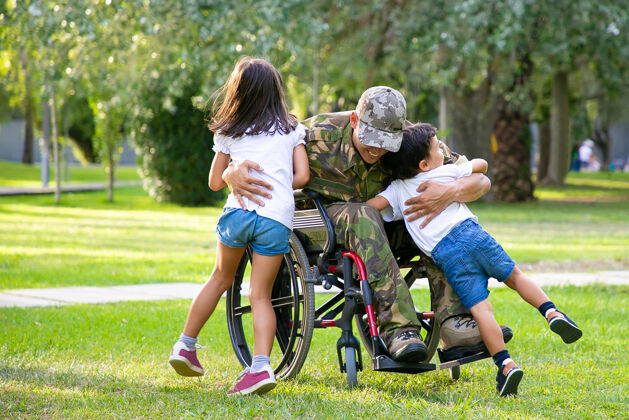 残疾人快乐残疾军人坐轮椅回家和孩子们拥抱老兵的战争或家庭团聚的概念军队男孩制服