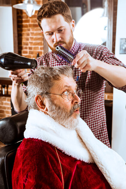 灯光圣诞前那个穿圣诞老人服装的老人在理发店给他的私人主人刮胡子男性肖像波基