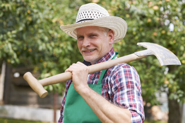 退休我准备好在花园里工作了站着成熟的人草帽