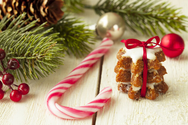 庆祝浅聚焦特写镜头的姜曲奇旁边的糖果藤和圣诞树枝树装饰品藤条
