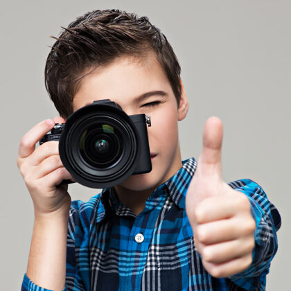 背景男孩拿着相机拍照少年男孩拿着单反相机向上展示拇指爱好摄影表演