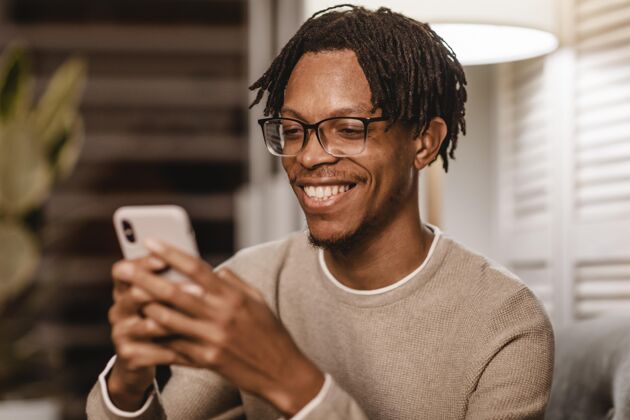 现代笑脸男在家使用现代智能手机设备家庭电子产品科技