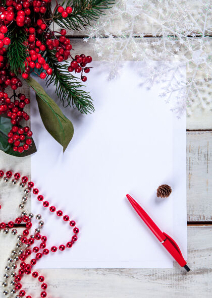 礼物纸上的空白纸上有一支钢笔和圣诞装饰品礼物 儿童 圣诞老人 雪花 桌子 花圈 庆典 信件 钢笔 礼物 书写 信息 木制 传统 乡村 书写 降临 床单 装饰 空白 乡村 空
