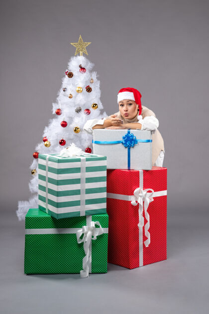 礼物漂亮的女人在灰色的礼物周围桌子圣诞树庆祝