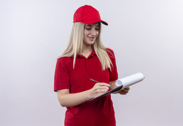 剪贴板带着微笑的小女孩穿着红色t恤 戴着帽子 戴着牙套 在白色背景的剪贴板上写字写作牙科支撑