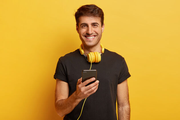 音乐快乐的白种人肖像享受美妙的声音和耳机质量 持有现代手机听音频休闲