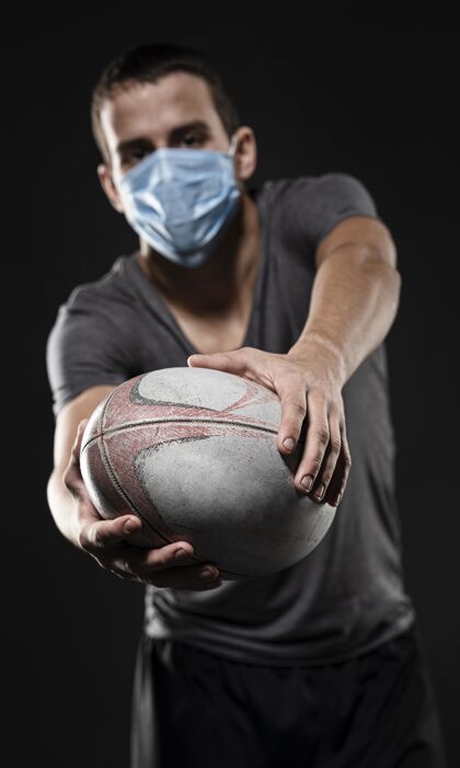活动手持医用面罩持球的男橄榄球运动员的前视图完全接触锦标赛体育