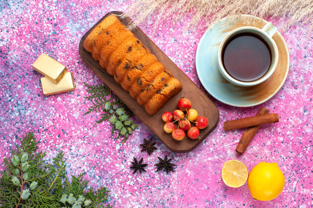 蛋糕俯瞰美味的蛋糕 甜甜可口的樱桃肉桂和一杯茶放在粉红色的桌子上烘焙甜味黄色