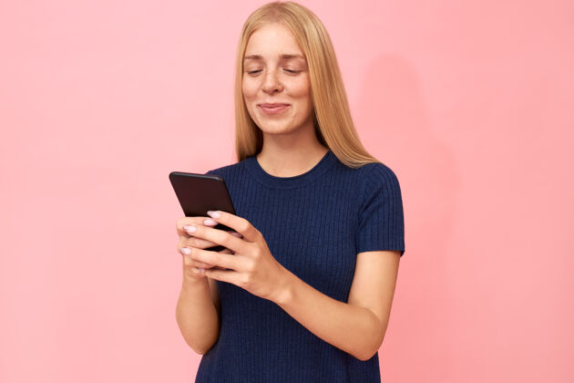 金发可爱时尚的少女通过智能手机上的高速互联网连接 通过社交网络滚动她的新闻源智能手机短信人物