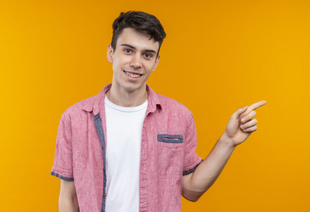 微笑微笑着的白人年轻人穿着粉色衬衫 指着旁边孤立的橙色背景侧边年轻点