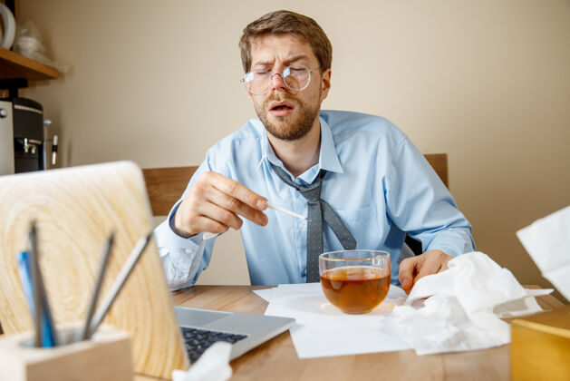 医疗感到恶心和疲倦在办公室工作的人喝一杯热茶 商人感冒 季节性流感大流行性流感 疾病预防 办公室空调引起疾病笔记本电脑茶员工