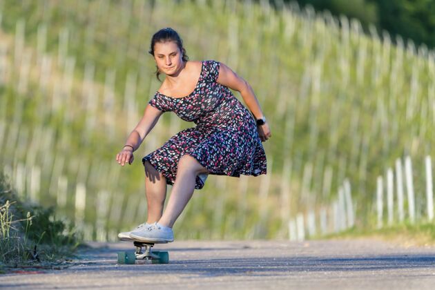 运动年轻女子在绿树环绕的空旷路上滑滑板年轻青年娱乐