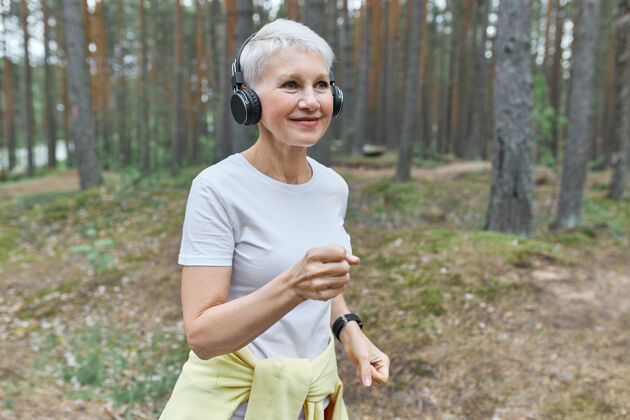 慢跑活跃成熟的女跑步者 穿着运动服 戴着无线耳机 听音乐戴着耳机听力女性锻炼