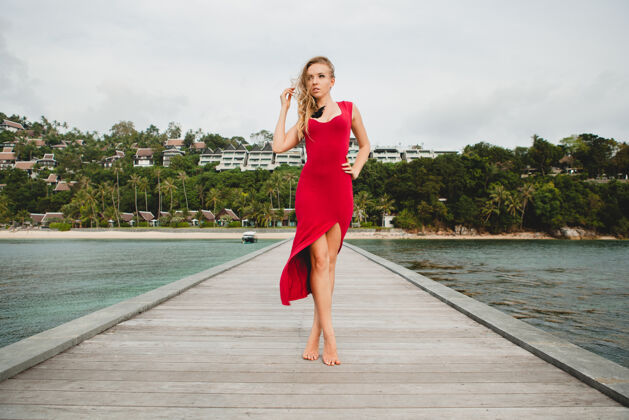 女性年轻漂亮迷人的女人独自站在豪华度假酒店的码头上 暑假 红色长裙 金色头发 性感服装 热带沙滩 诱惑 性感 微笑年轻性感时尚