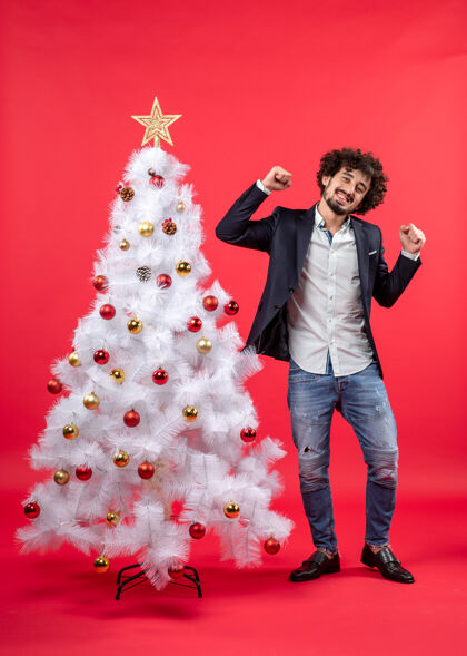 有趣的男人圣诞庆祝与年轻的快乐兴奋有趣的男子站在圣诞树旁跳舞快乐树装饰