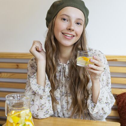 食品中镜头美女端坐在桌边拿着柠檬水杯食品美味垂直