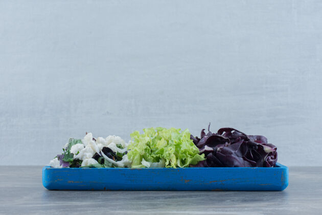 花椰菜在大理石上放着切碎的卷心菜 花椰菜和苋菜的蓝色盘子什锦胃口托盘