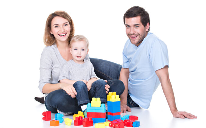 夫妇快乐微笑的年轻父母与婴儿玩耍的肖像-白色隔离孩子玩具三