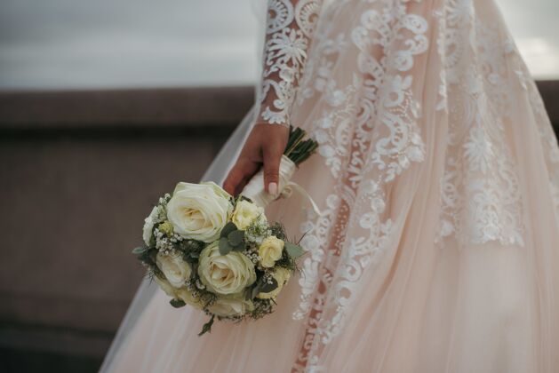 软新娘穿着漂亮的婚纱 捧着她婚礼当天的一束美丽的玫瑰订婚玫瑰新娘