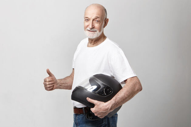 摩托车一张没有刮胡子的欧洲男性身穿休闲t恤手持摩托车头盔的照片服装摩托车好