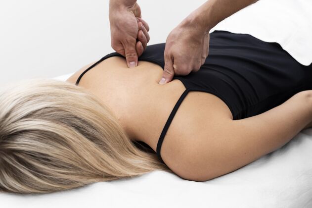 治疗理疗师给女病人做背部按摩背部损伤治疗