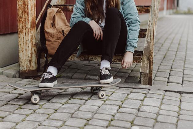 练习滑冰女孩在市区坐在楼梯前看滑板日光年轻