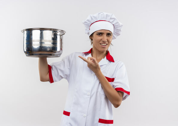 厨师困惑的年轻女厨师穿着厨师制服拿着点平底锅在隔离的白色墙壁上复制空间年轻穿混乱