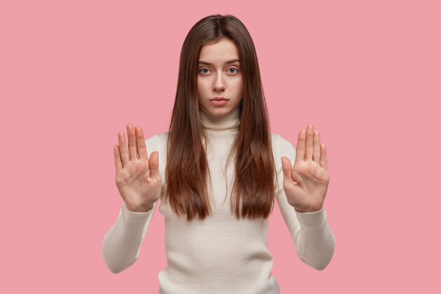 性格禁止标志严肃自信的女人展示手掌 展示停止标志 长直发 令人愉快的样子手掌拒绝女性