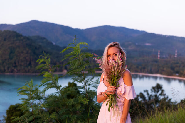 自然穿着夏装的年轻白种女人的浪漫写真 在山上的公园里享受着令人惊叹的热带海景度假积极紫色