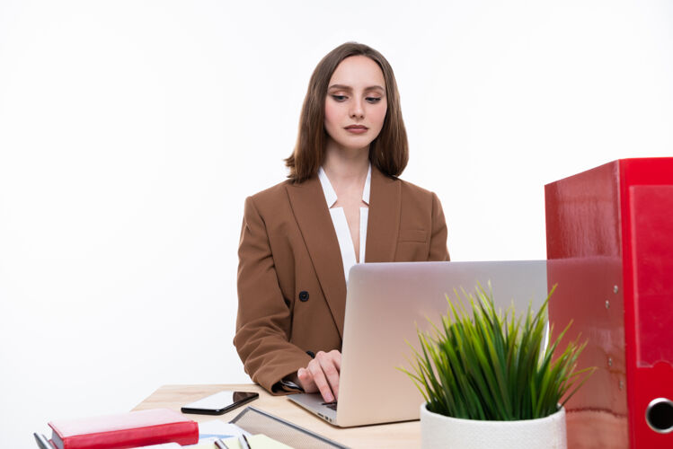 行政一个穿着西装的年轻女子在一台白色背景的笔记本电脑前工作孤立的工作场所美丽模特