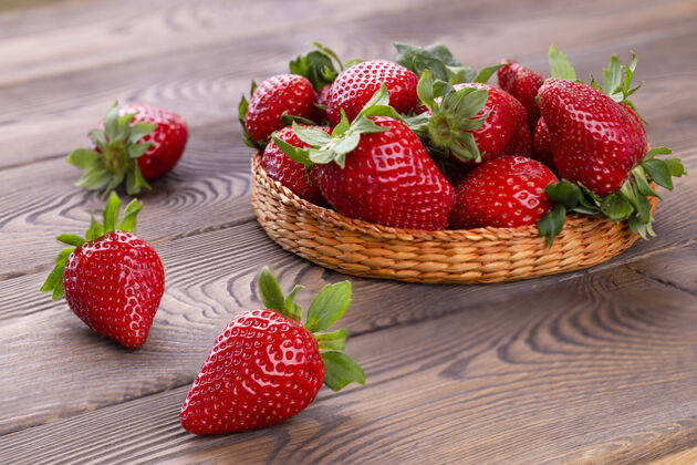 自然一个柳条碗里的多汁草莓 放在一张破旧的白色木桌上 乡村风格生的餐桌农业