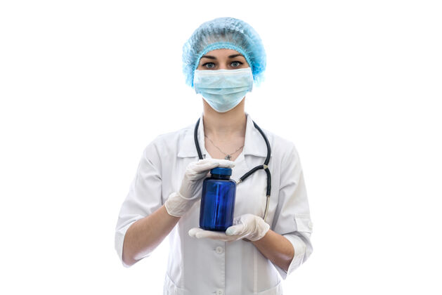 护士医生把蓝色瓶子隔离在白墙上摆姿势药物医生面具
