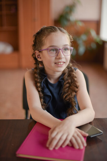 童年教室里坐在桌子旁拿着课本的女学生一个穿着蓝色裙子扎着辫子的女孩学校桌子知识