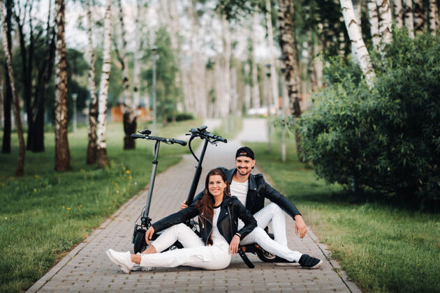 女人一对情侣坐在电动滑板车旁 一起享受大自然的时光 两个恋人骑着电动滑板车滑板车休闲浪漫
