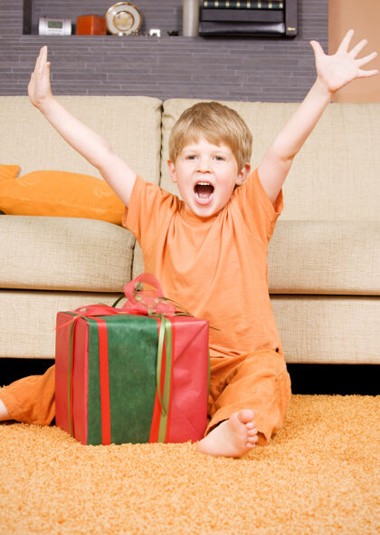 乐观带着大礼盒的快乐男孩圣诞节欢呼年轻人