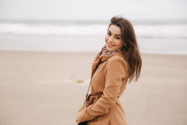 女人美丽女子在北海沿岸散步的肖像穿着棕色外套的优雅女士海滩微笑成年人
