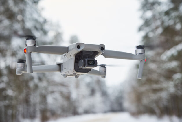技术带相机的无人机四架直升机在冬天的森林里飞行运动远程车辆