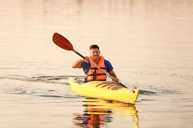 运动年轻人在河里划独木舟划桨休闲娱乐